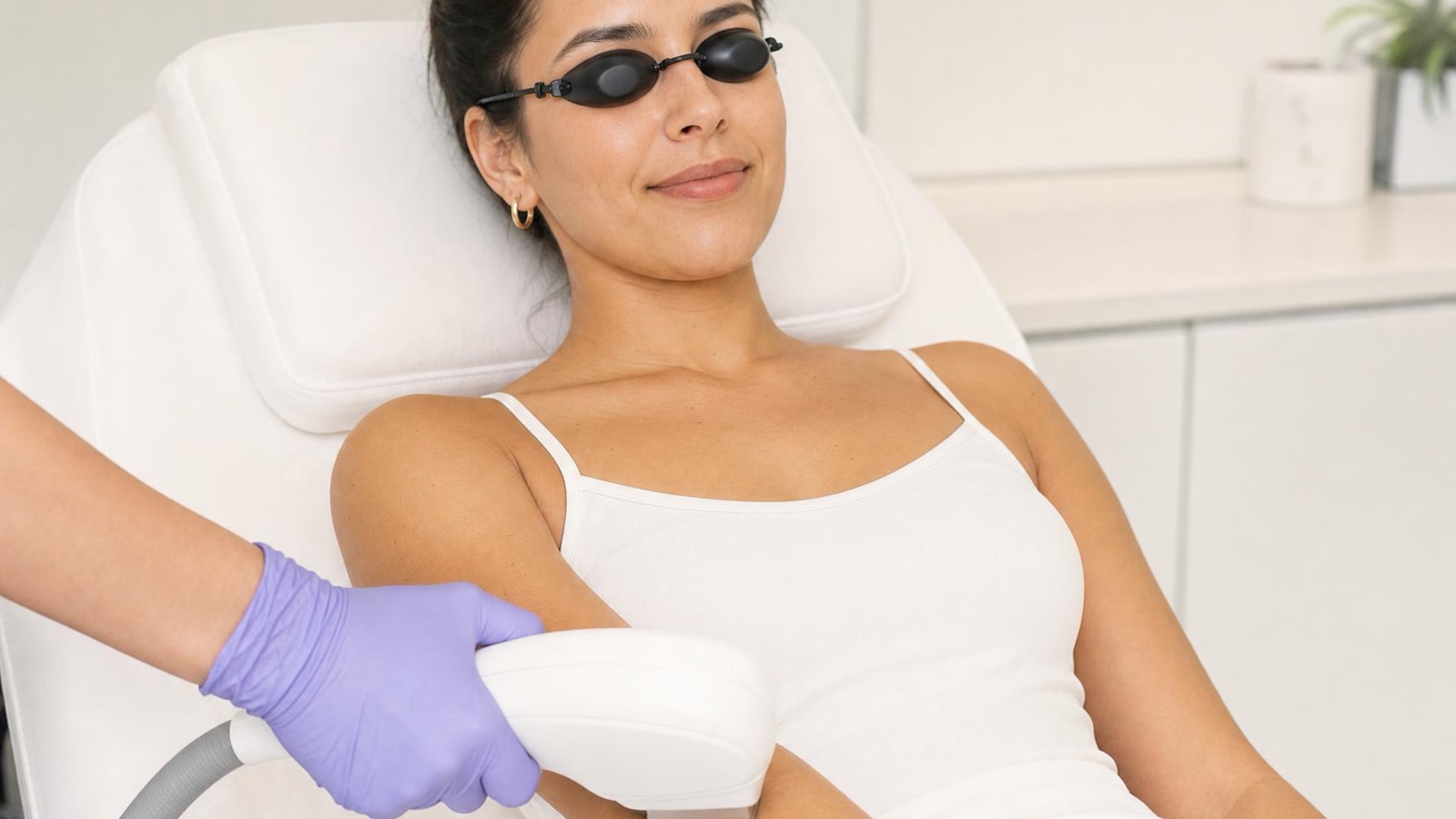 Relaxed client in protective goggles during laser hair removal on her forearm